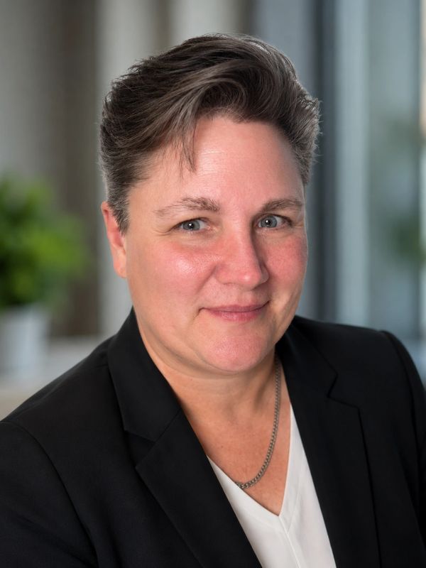 Professional portrait of a person with short hair in a black blazer.