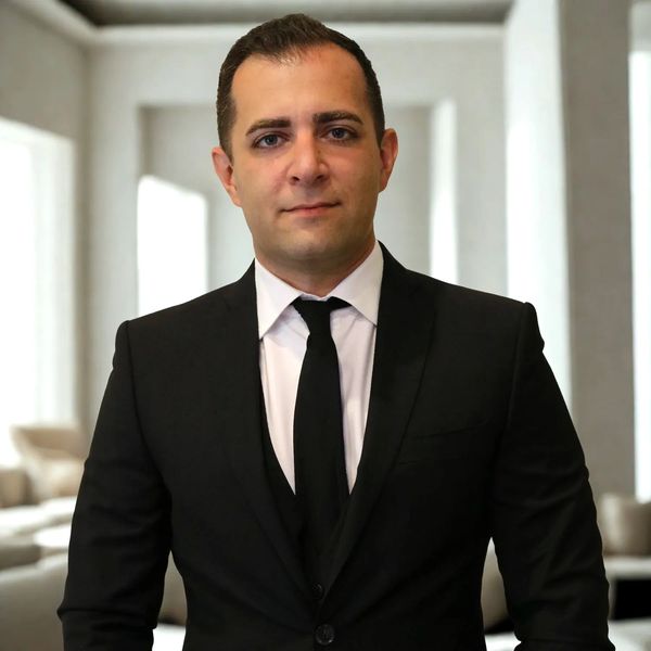 Professional man in a black suit and tie, standing confidently indoors. Your Woodland Hills real estate agent. 