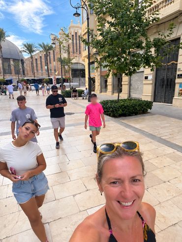 Group walking on a sunny street with smiles and casual clothes.