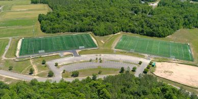 Aerial view of two sports fields surrounded by trees.
