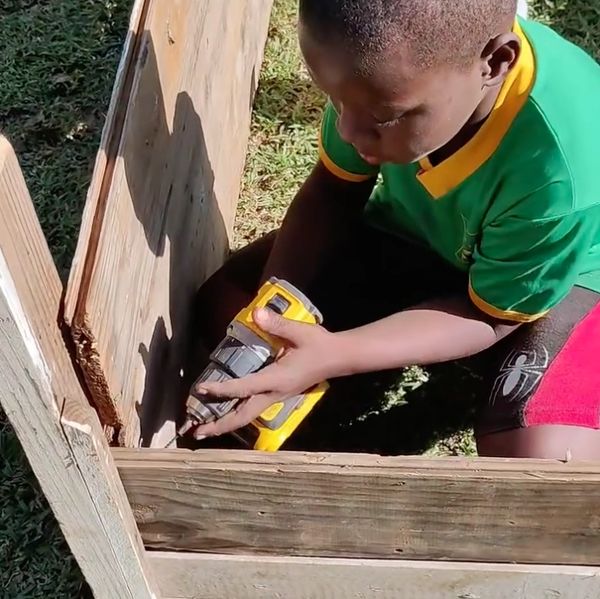 Boy using a drill on wooden boards.