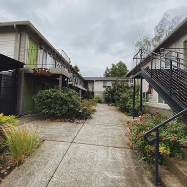 Outdoor walkway between apartment buildings on a cloudy day.