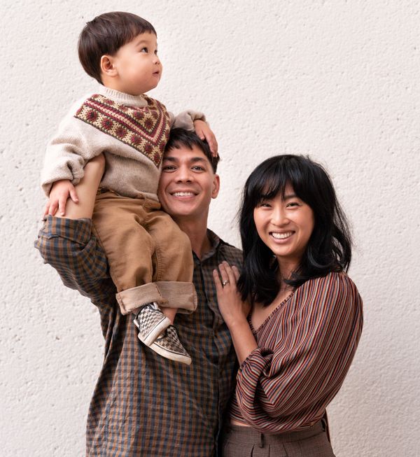 Happy family portrait with a man holding a child and a smiling woman beside them.