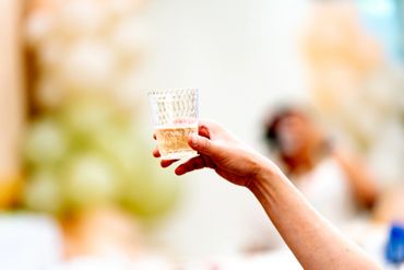 Hand holding a glass for a toast at a celebration.