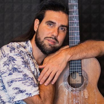Hombre apoyado en una guitarra acústica.