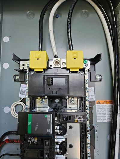 Close-up of a circuit breaker panel with labeled breakers and wires.