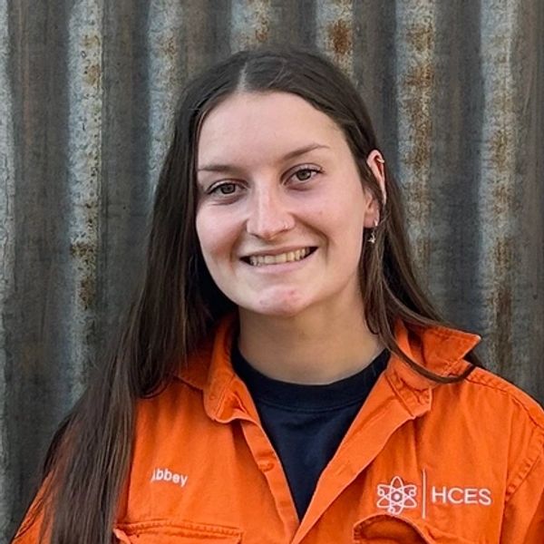 Young woman smiling in orange work uniform.