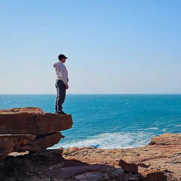 woman standing on coastal ledge - symbolizing reflection, resilience, and a journey toward healing