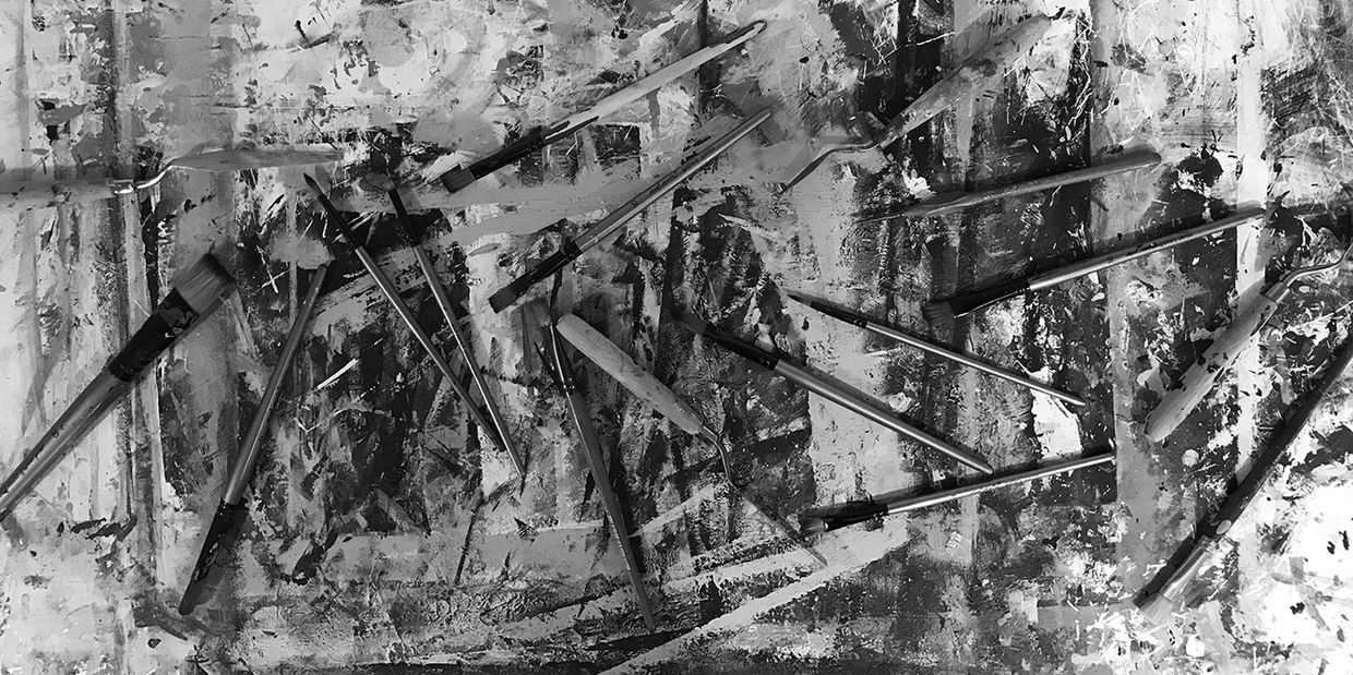 Paint brushes and palette knives scattered on artist Lynka work table