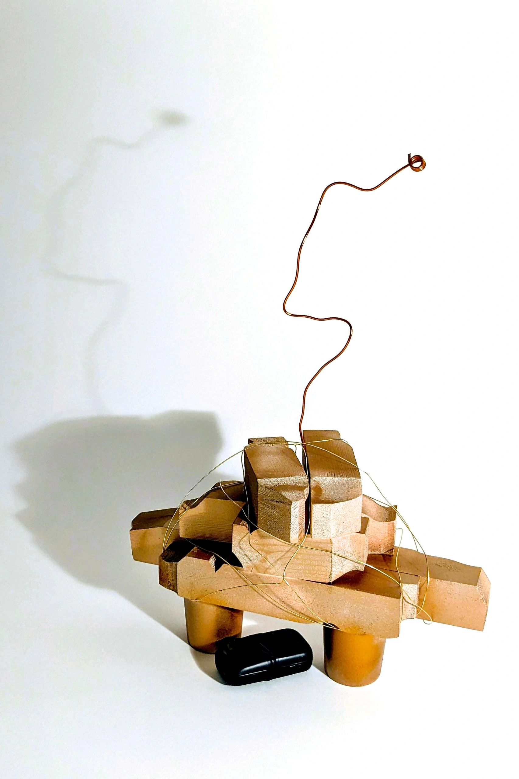 Abstract sculpture made of wooden blocks and wire with a white background.