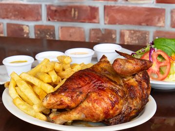 Rotisserie chicken served with crispy fries and dipping sauces.