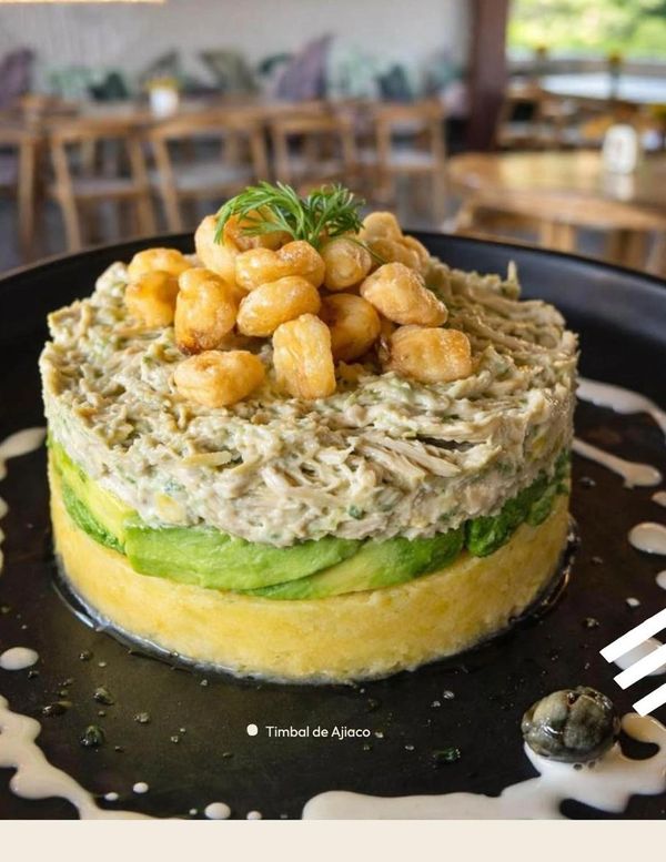 Timbal de Ajiaco with layered ingredients and corn on top.