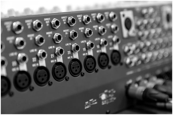 Close-up of audio mixer input and output jacks in black and white.