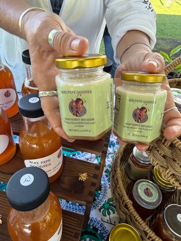 Two jars of Wai Pepe Goodies Raw Honey Infusion held by a person.