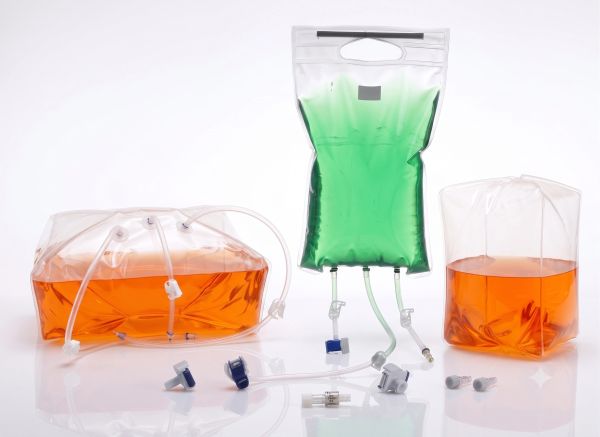 Flexible plastic infusion or collection bags with orange and green liquids.