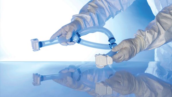 Gloved hands assembling or inspecting a flexible medical or laboratory tubing device.