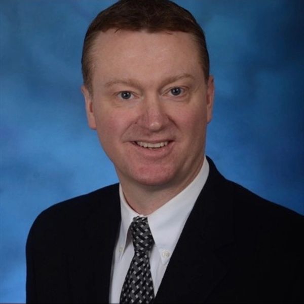 Professional headshot of an experienced pilot in a suit and tie.