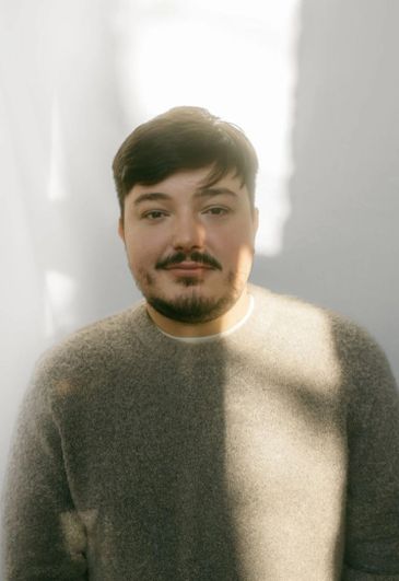Man with a beard in soft lighting and a cozy sweater.