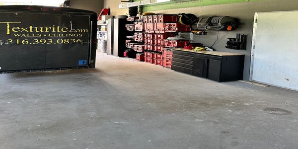 Organized workshop with tools, cabinets, and a company trailer inside a garage.