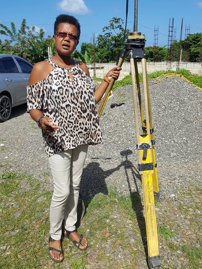 Woman standing outdoors with surveying equipment.