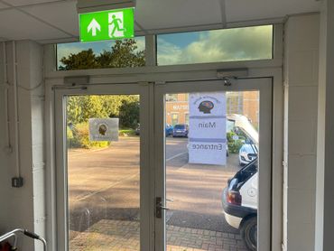 Glass double doors with exit sign and main entrance sign outside.