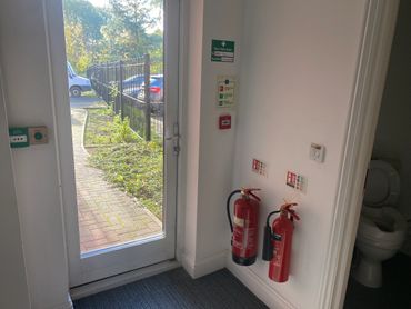 Emergency exit door with fire extinguishers and a restroom visible.