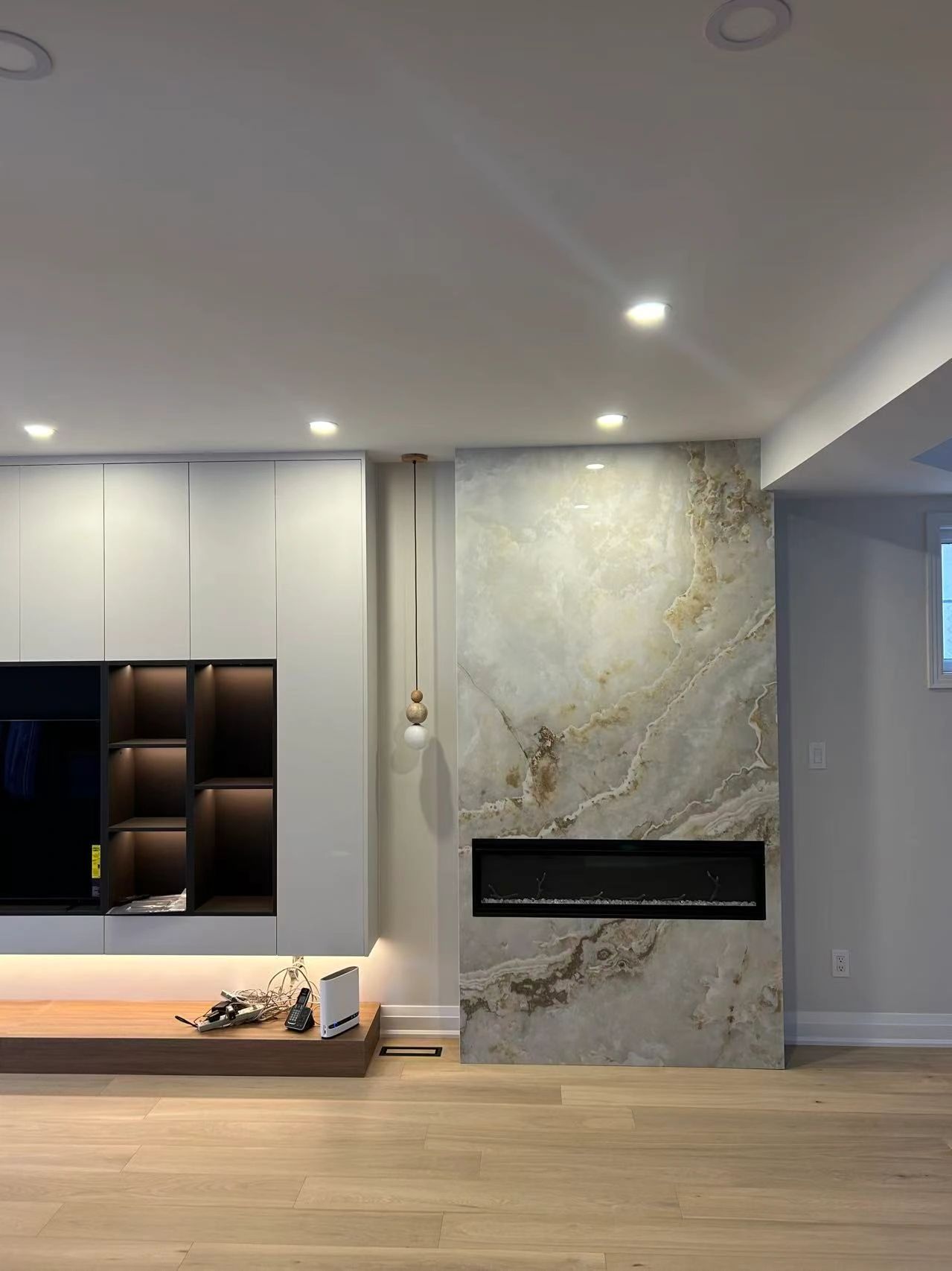 Modern living room with sleek cabinetry, a marble fireplace, and warm wooden flooring.
