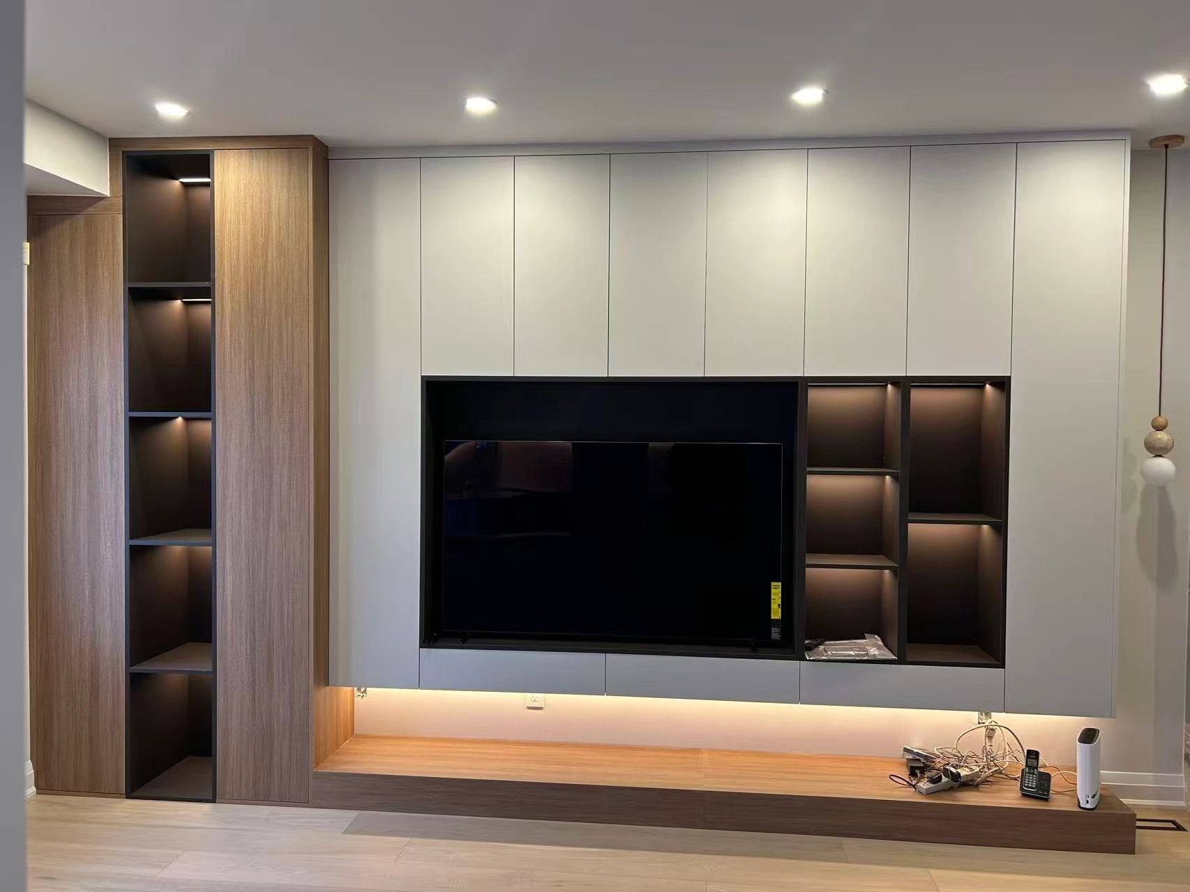 Modern TV unit with white and wood finish, ambient lighting, and open shelves.