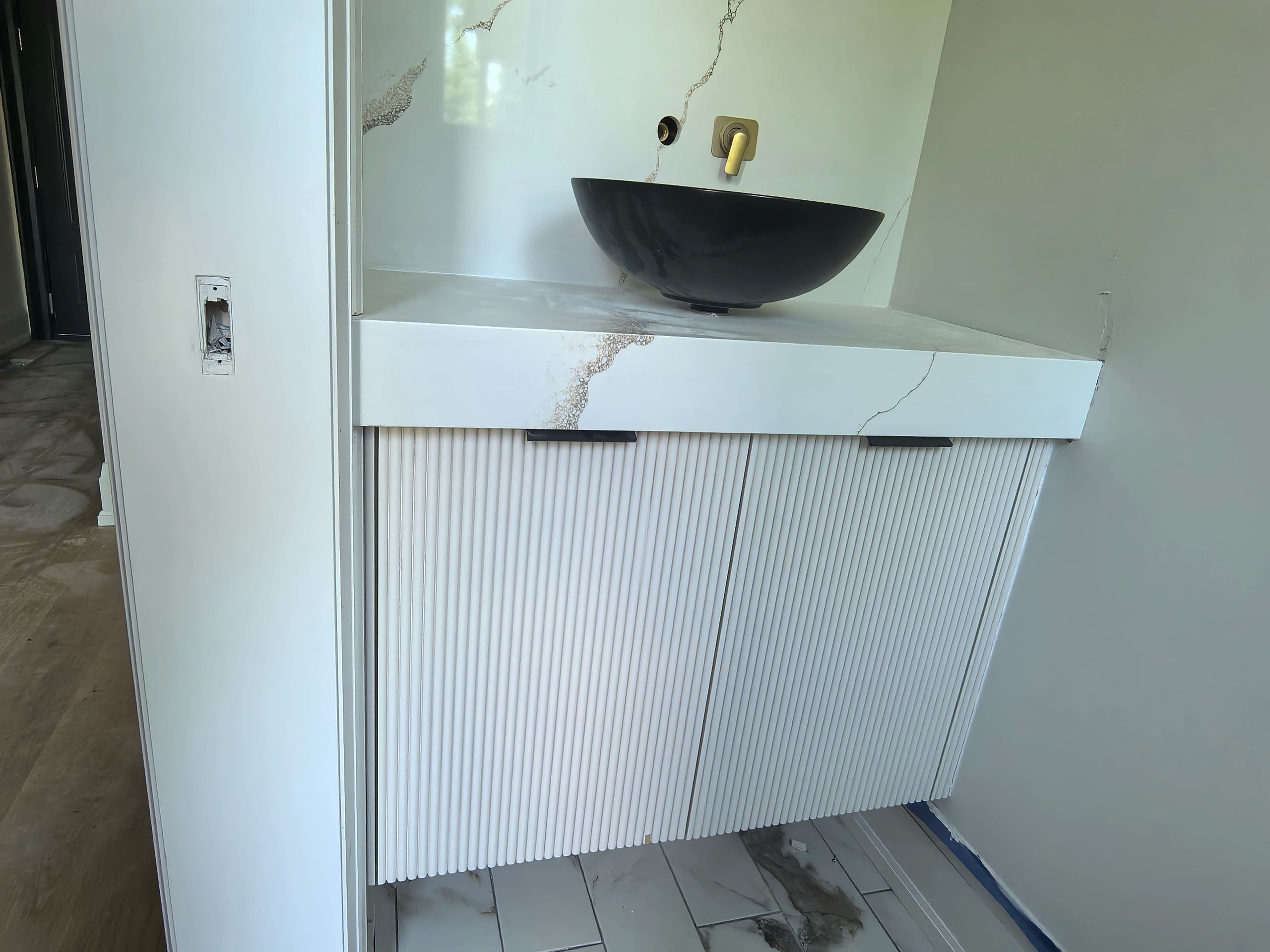Modern bathroom sink with black basin and cracked marble counter.