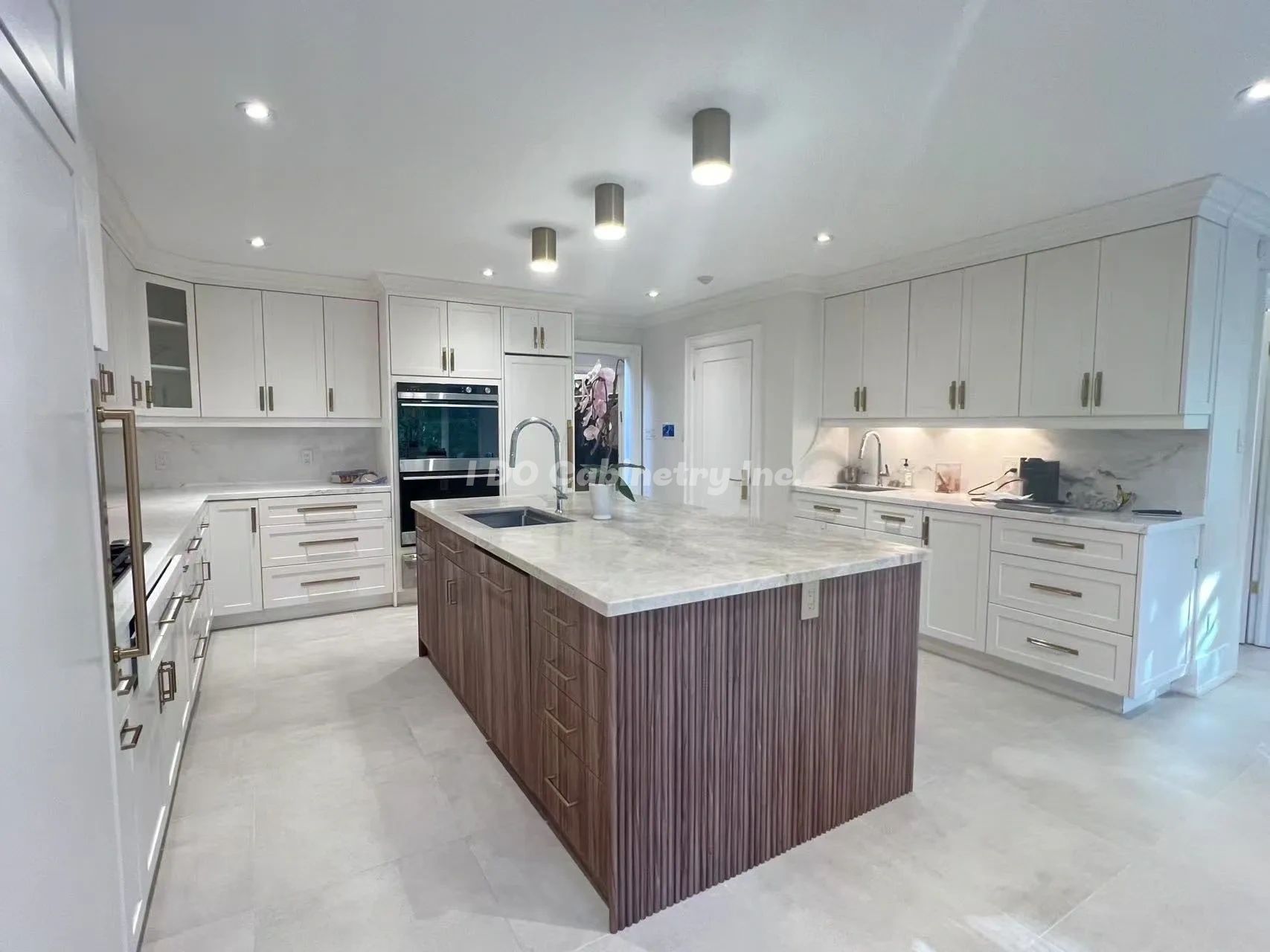 Modern kitchen with white cabinets and a large island featuring wood paneling.