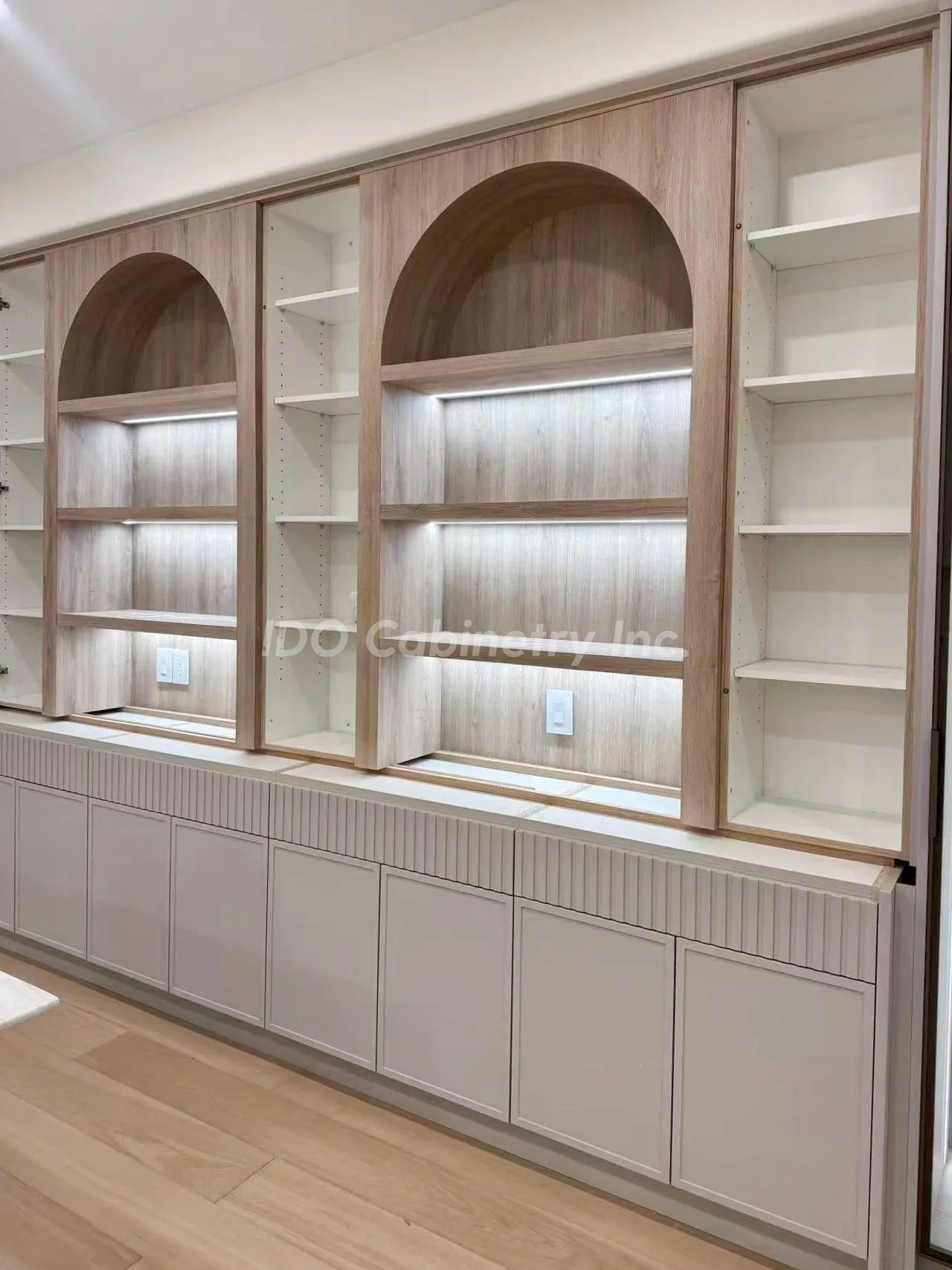 Modern wooden cabinetry with arched shelves and built-in lighting.