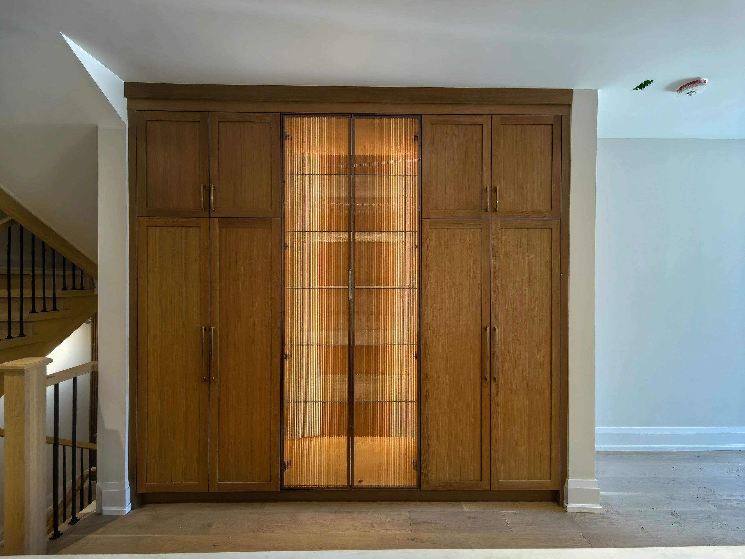 Wooden cabinet with central ribbed glass doors.