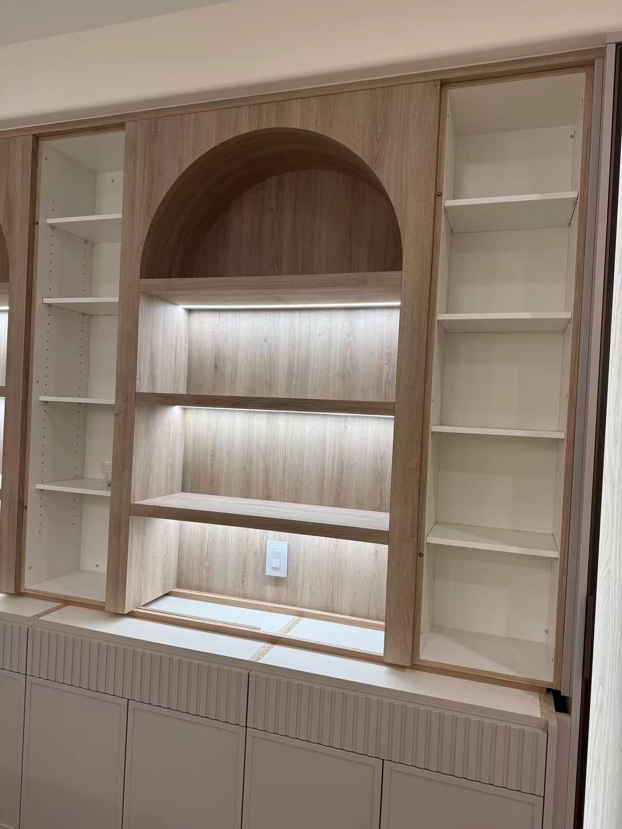 Modern wooden shelving unit with LED lighting and white side shelves.