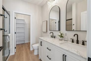 Modern bathroom with double sink and walk-in closet.
