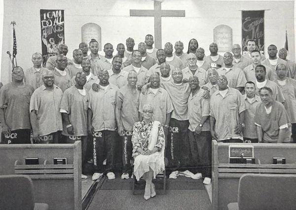 Group photo of prisoners and a woman in a church setting.