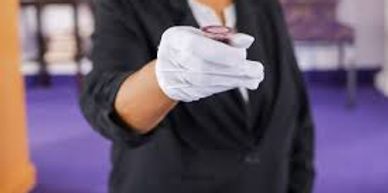 Person in gloves holding a small round object towards the camera.