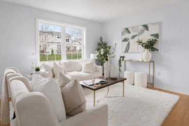 Bright and cozy living room with white furniture and greenery.