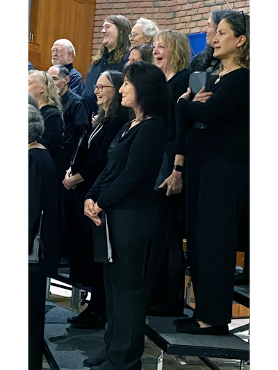 Smiling members of Capella Nova standing on risers at the winter concert. 