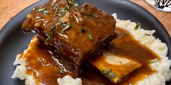 Braised beef short ribs with gravy over mashed potatoes.
