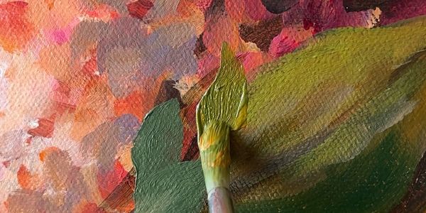 Close-up of a paintbrush applying green paint on a textured canvas.