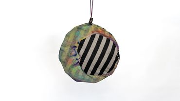 Round multicolored ornament with black and white stripes.