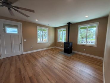 Empty living room with wood flooring and a black stove.
