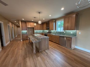 Spacious kitchen with wooden floors and cabinets, featuring a central island and modern appliances.