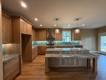 Modern kitchen with wooden cabinets and granite countertops under warm lighting.