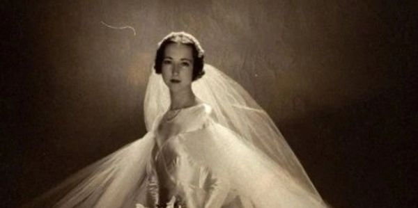 Vintage black-and-white photo of a bride in an elegant wedding gown with a flowing veil.