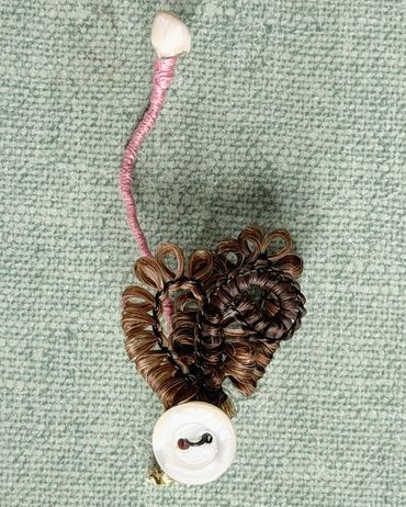 Brooch made with human hair, baby tooth and mother of pearl button