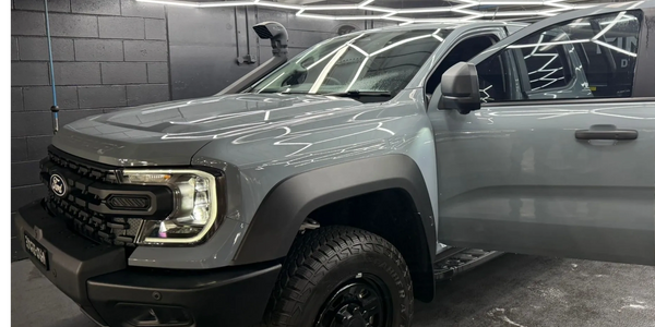 Gray Ford pickup truck with off-road tires in a garage.