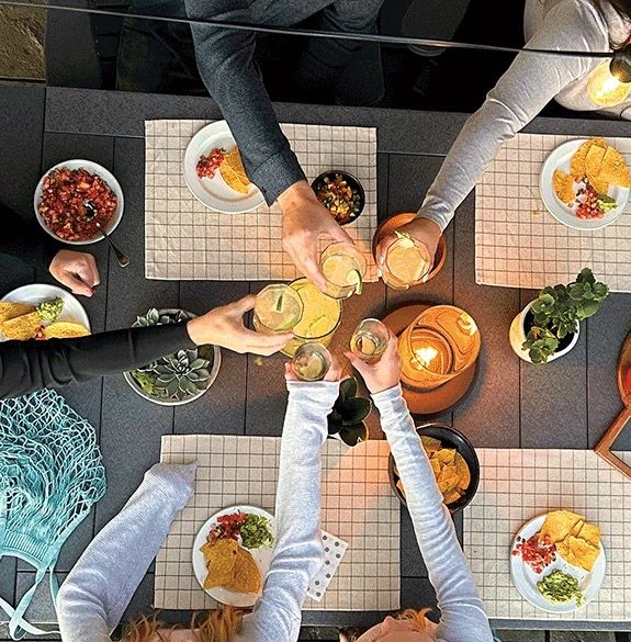 Food and drinks with friends on patio at Tru180 outdoor table. 
