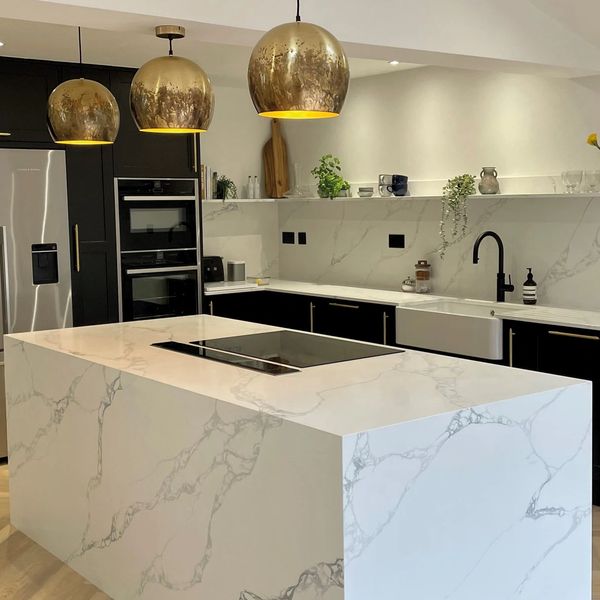 Modern kitchen with marble island and gold pendant lights.