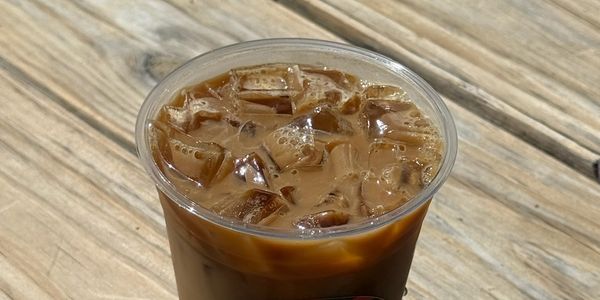 Iced coffee in a plastic cup on a wooden table.